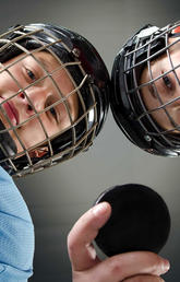 image of two kids wearing hockey gear holding a puck