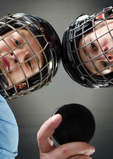 photo of two kids in hockey uniforms holding a puck